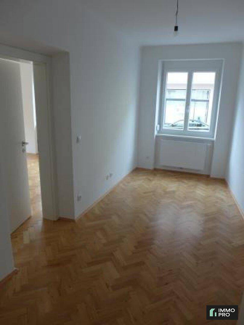 Kleineres Zimmer mit Parkettboden und Fenster, ideal als Schlafzimmer oder Arbeitsbereich.