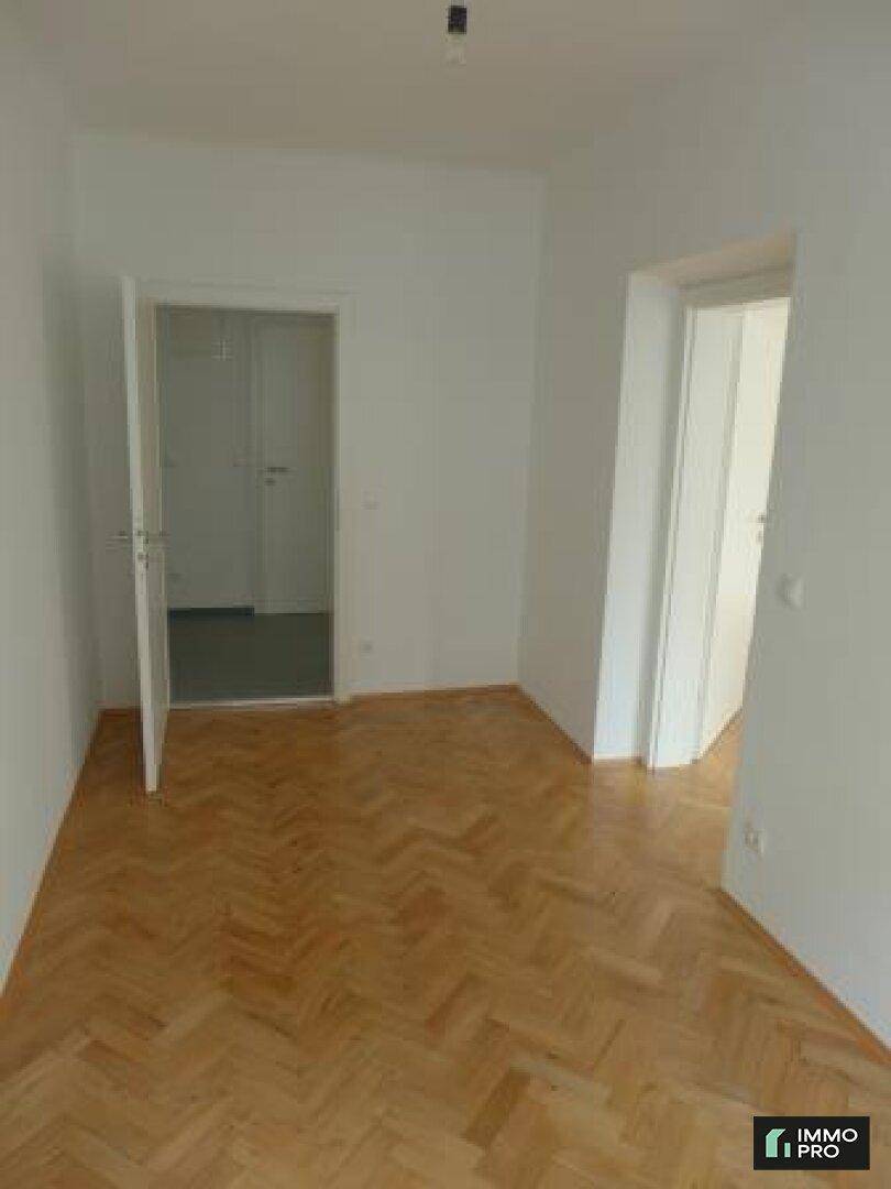 Helles Zimmer mit Parkettboden und zwei Türen, bietet flexible Nutzungsmöglichkeiten.