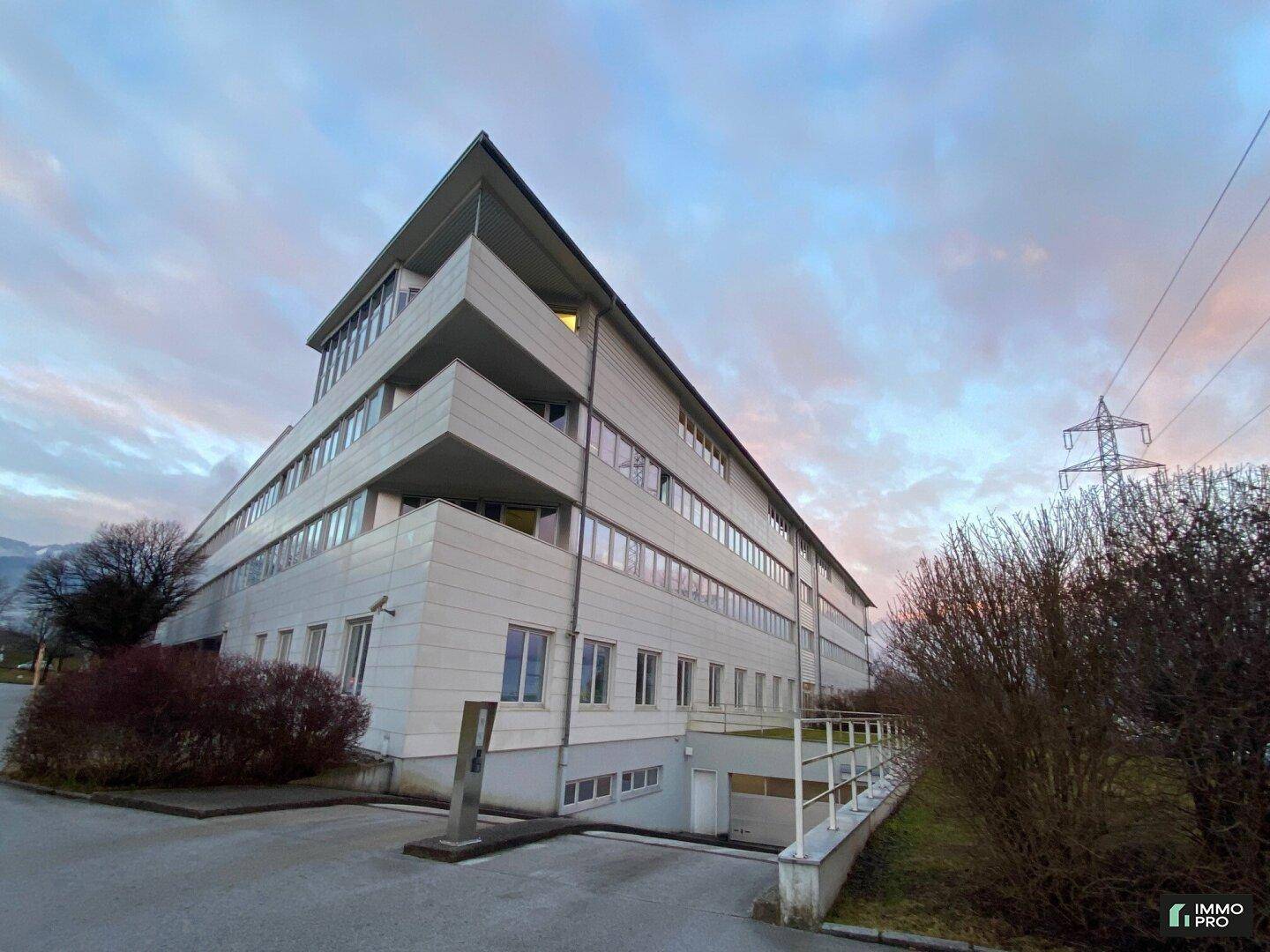 Gesamtansicht des modernen Bürogebäudes mit mehreren Etagen und einer Zufahrt zur Tiefgarage.