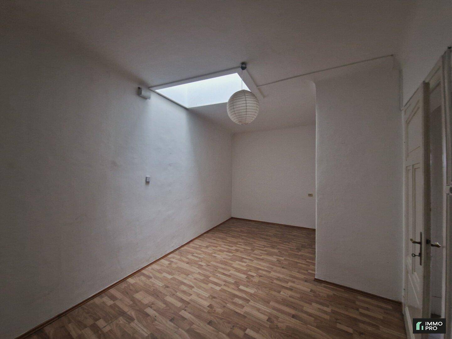 Lichtdurchfluteter Raum mit Laminatboden, Oberlicht und einer modernen Hängelampe, ideal für viele Nutzungen.