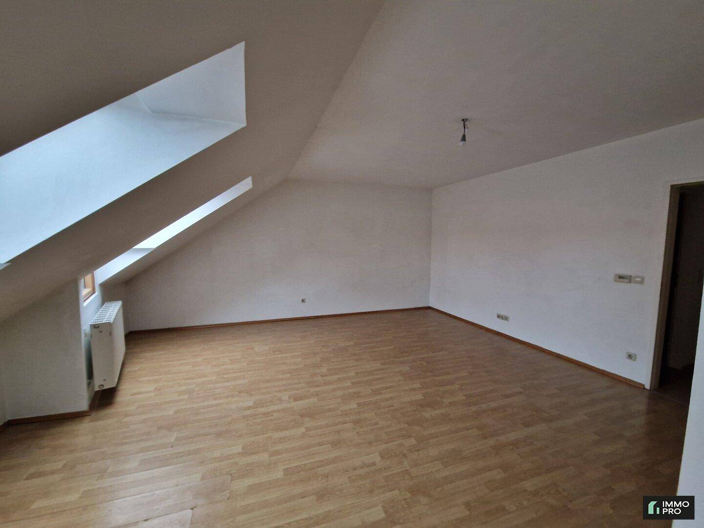 Heller Dachgeschossraum mit Laminatboden und schrägen Wänden, ideal für individuelle Gestaltung.