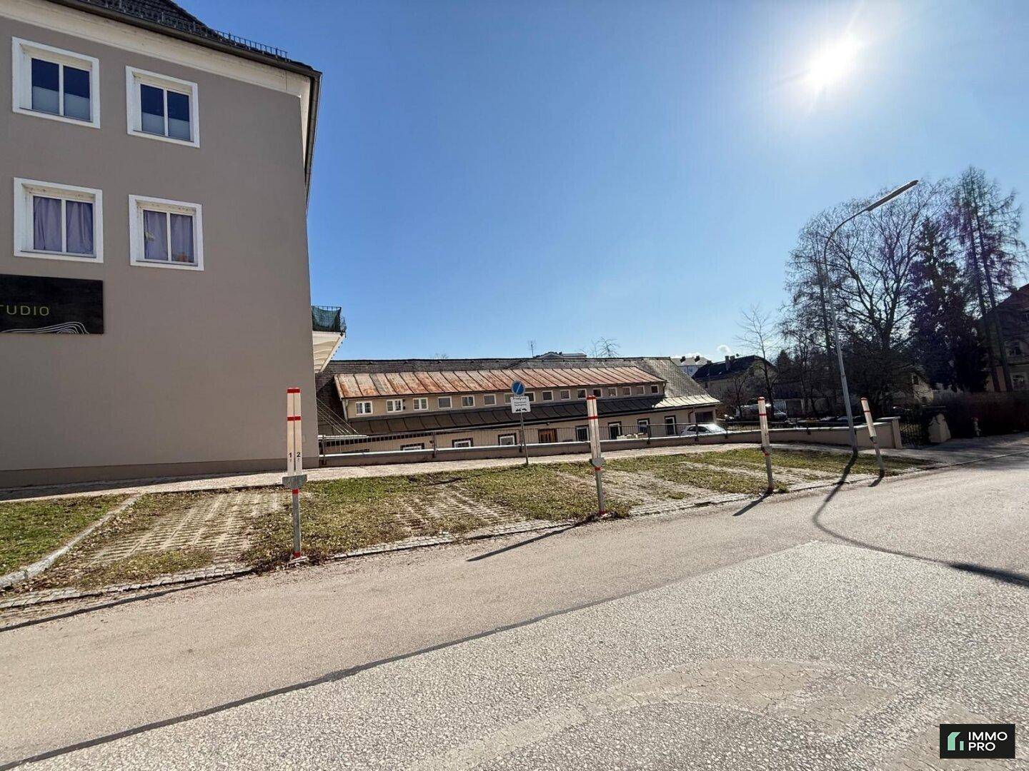 Außenansicht eines Gebäudes mit Parkplätzen davor unter strahlend blauem Himmel.
