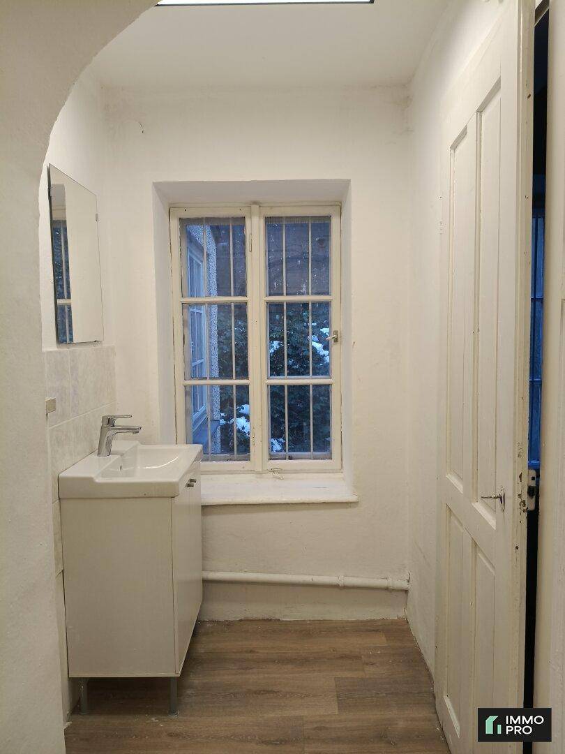 Badezimmer mit Waschbecken, Spiegelschrank und einem Fenster, das für Tageslicht sorgt.