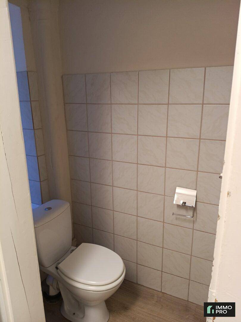 Separate Toilette mit hellen Fliesen an der Wand und einem funktionalen WC.