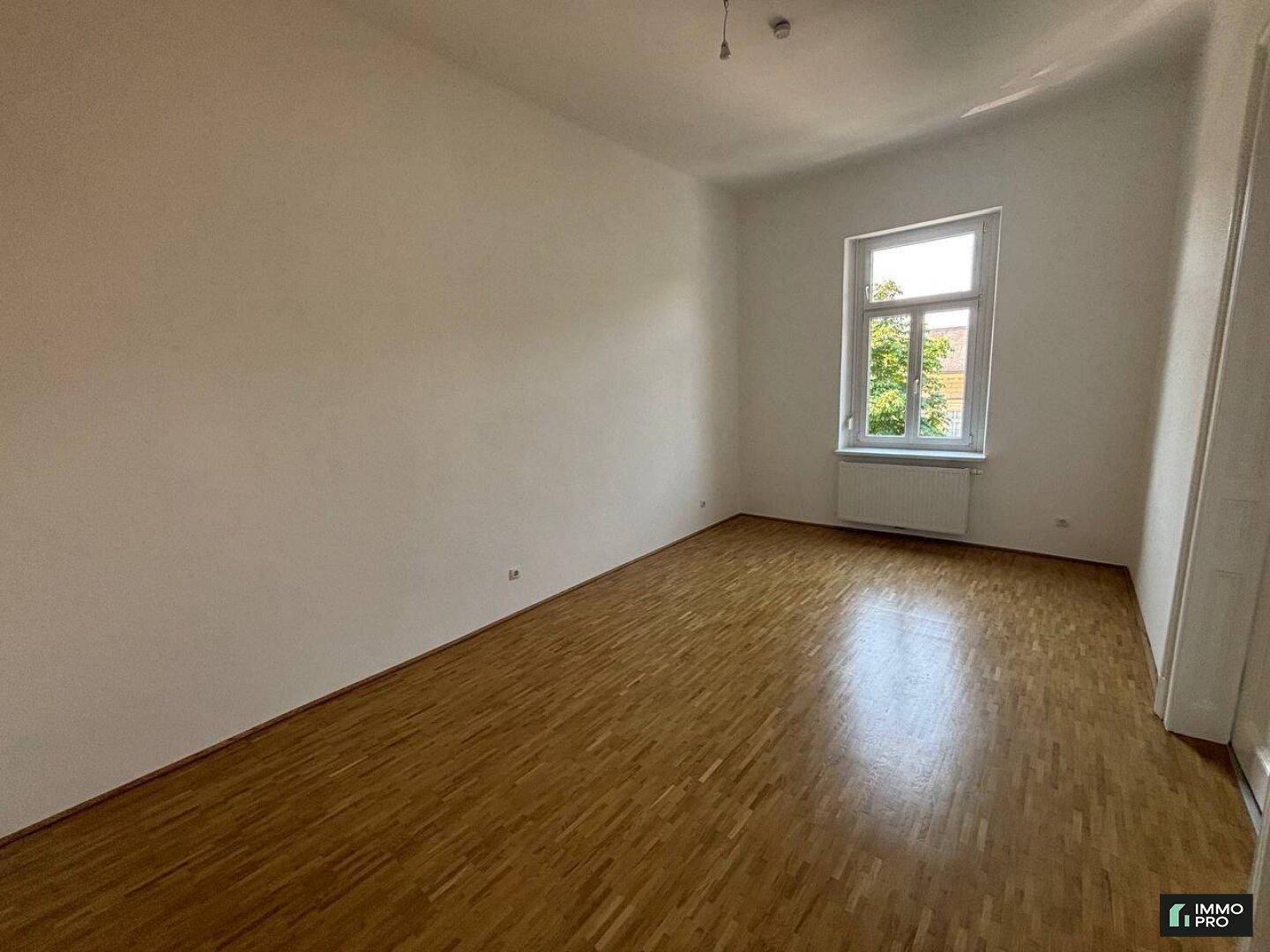 Geräumiges Zimmer mit hellem Parkettboden und einem Fenster, das für gute Belichtung sorgt.