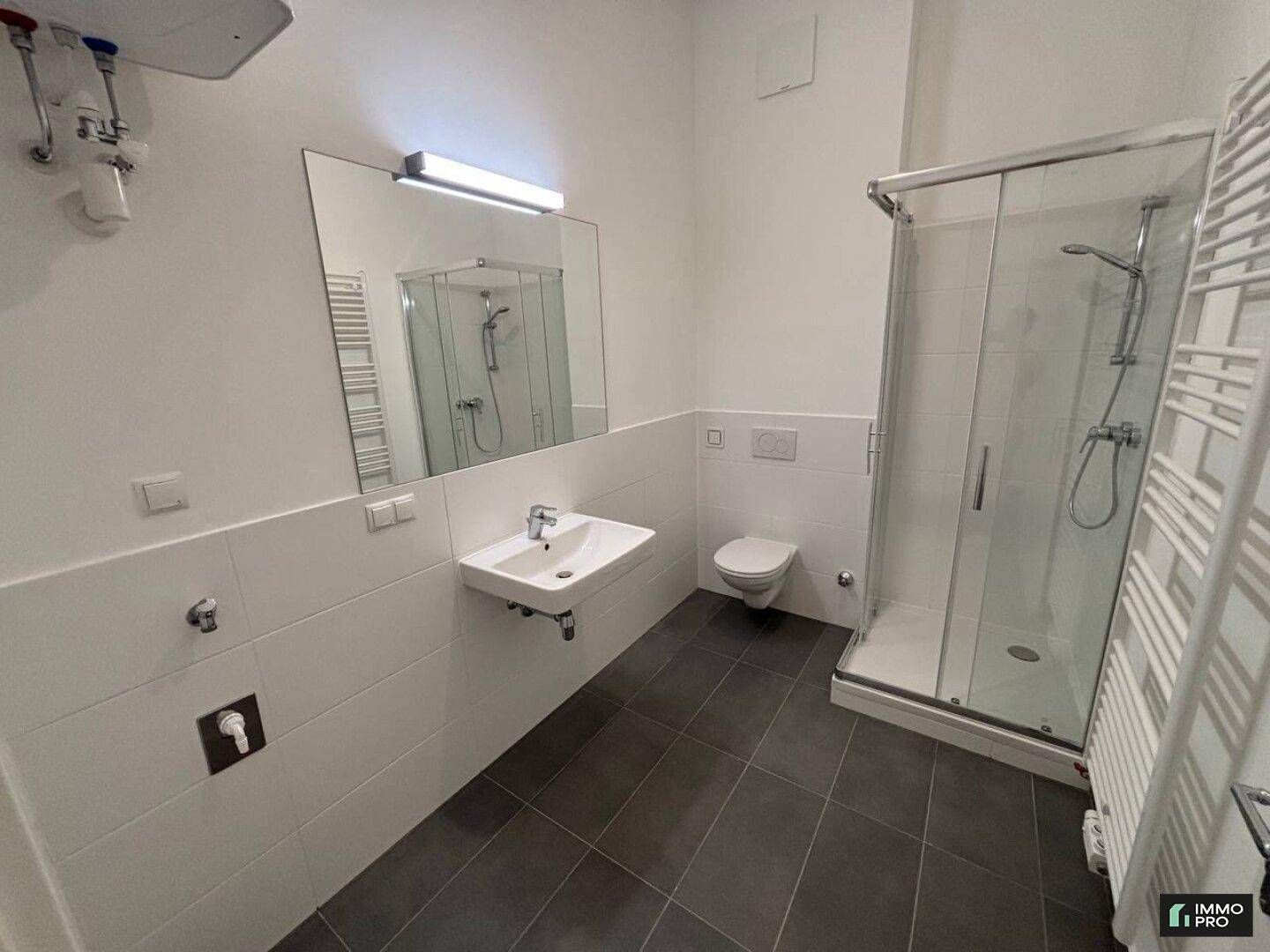 Modernes Badezimmer mit Duschkabine, WC, Waschbecken und beheiztem Handtuchhalter.