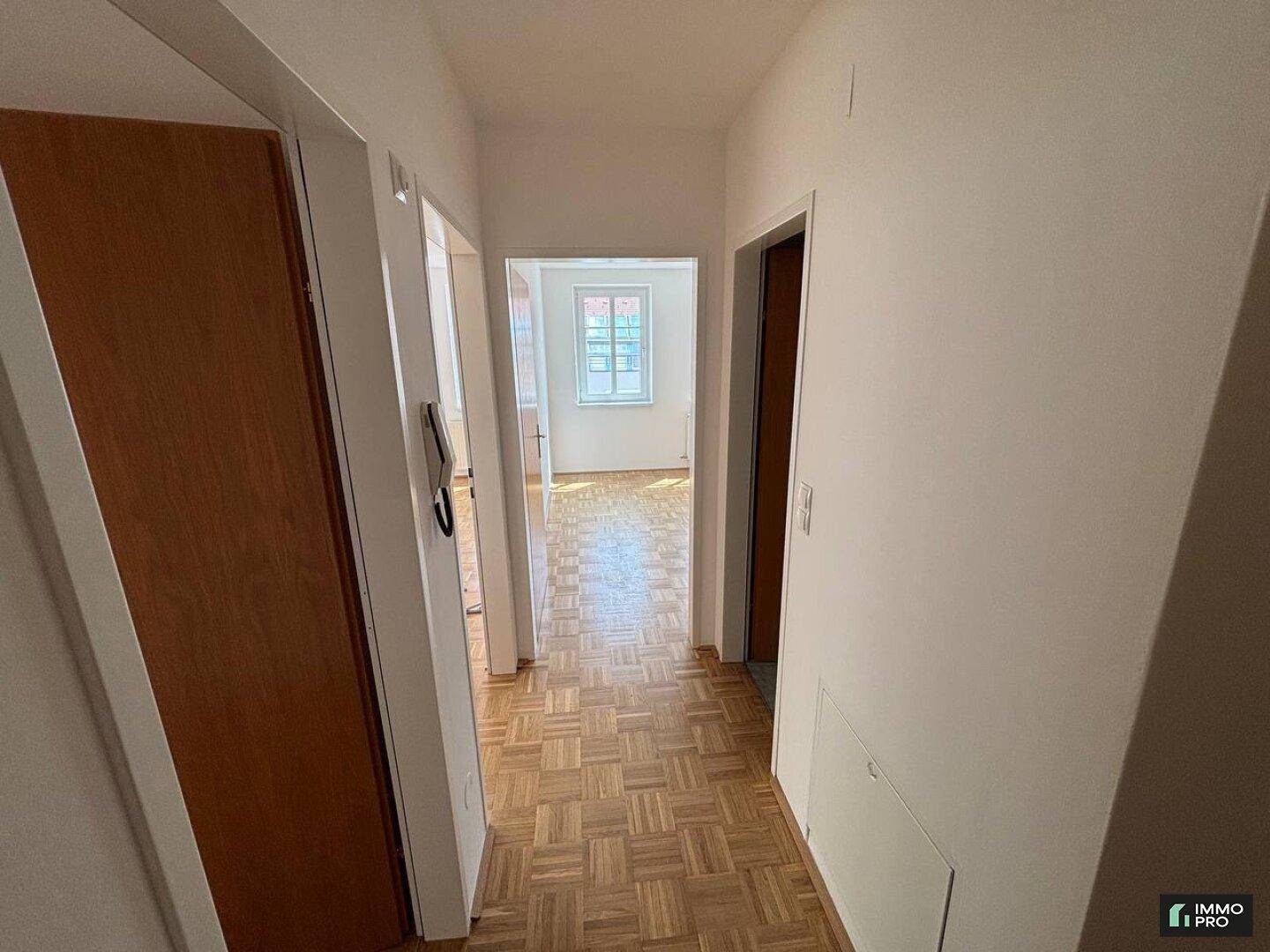 Heller Flur mit Parkettboden, Holztüren und Blick in ein weiteres Zimmer.