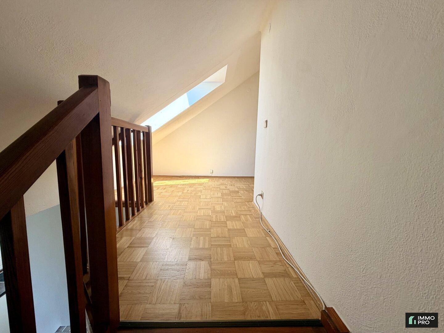 Heller Flurbereich im Dachgeschoss mit Parkettboden und natürlichem Licht durch Dachfenster.