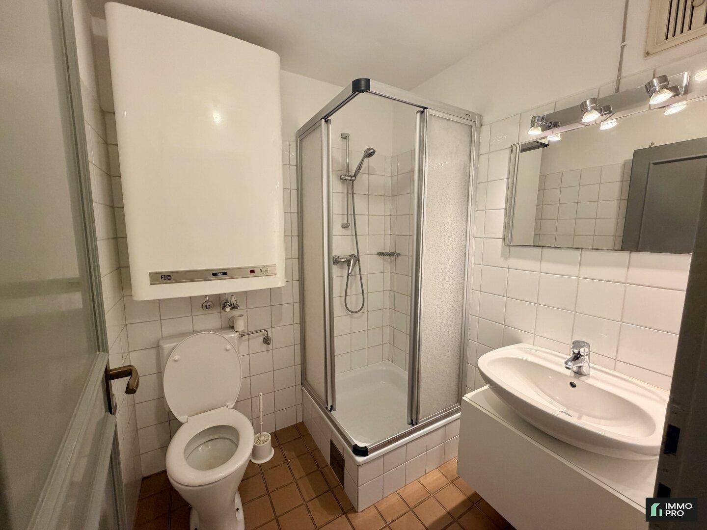 Funktionales Badezimmer mit Duschkabine, WC, Waschbecken und Fliesenboden.