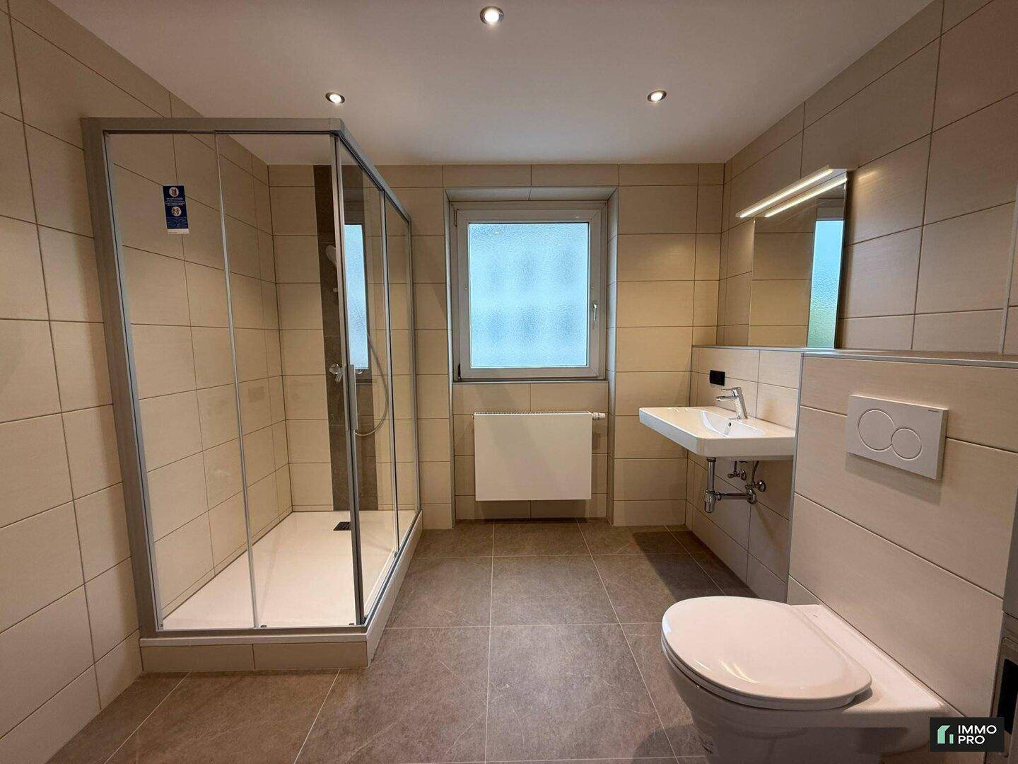 Helles Badezimmer mit begehbarer Dusche, wandhängendem WC und modernem Waschbecken.