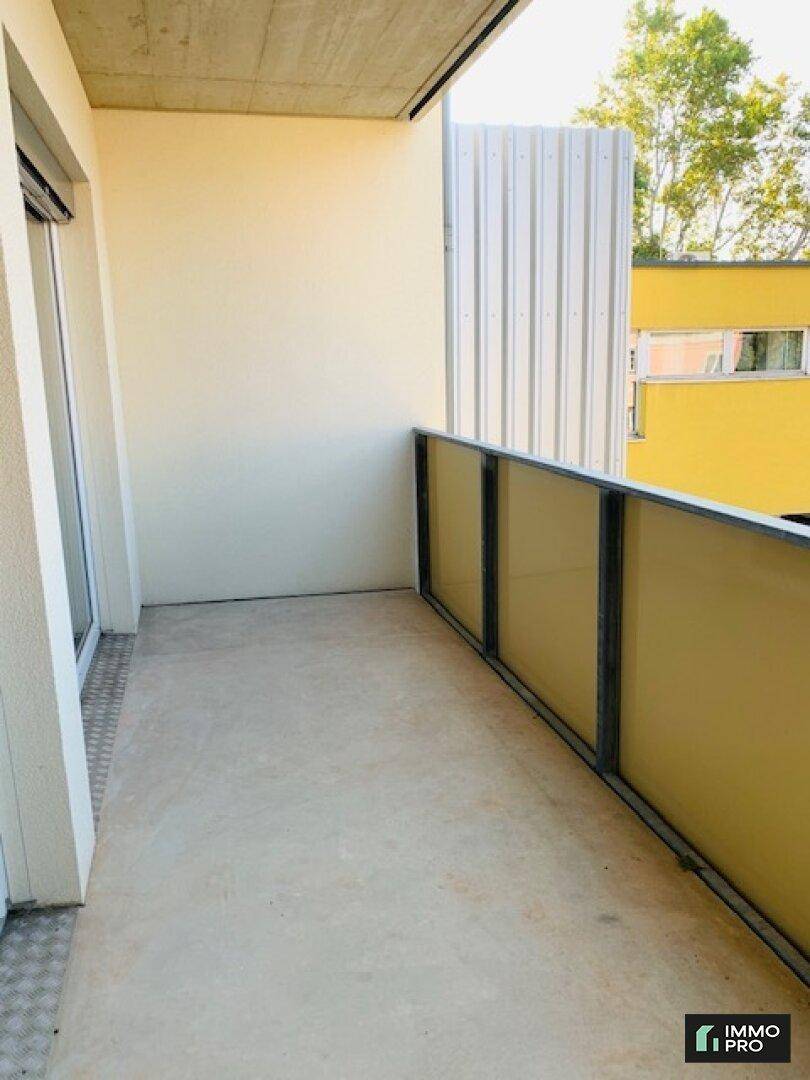 Heller Balkon mit Betonboden und Glasgeländer, bietet einen Blick auf die umliegenden Gebäude.