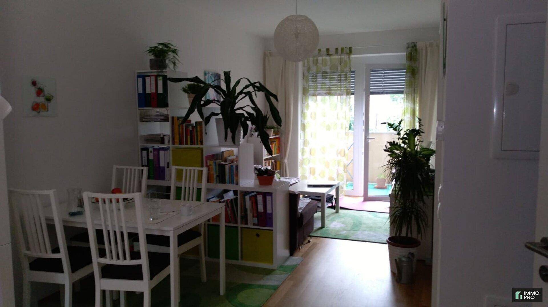Gemütlicher Wohn- und Essbereich mit Bücherregal und direktem Zugang zu einem Balkon.