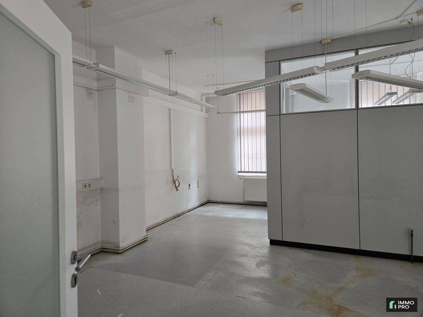 Heller Büroraum mit Trennwänden und Deckenleuchten, ideal für flexible Arbeitsplatzgestaltung.