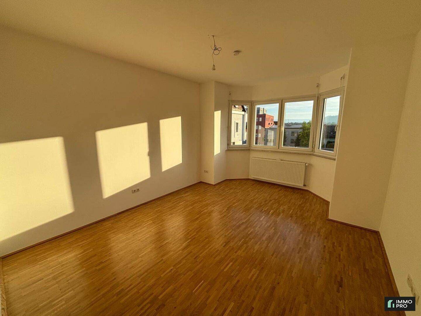 Sonnenverwöhntes Zimmer mit Erkerfenstern, Parkettboden und viel natürlichem Lichteinfall.