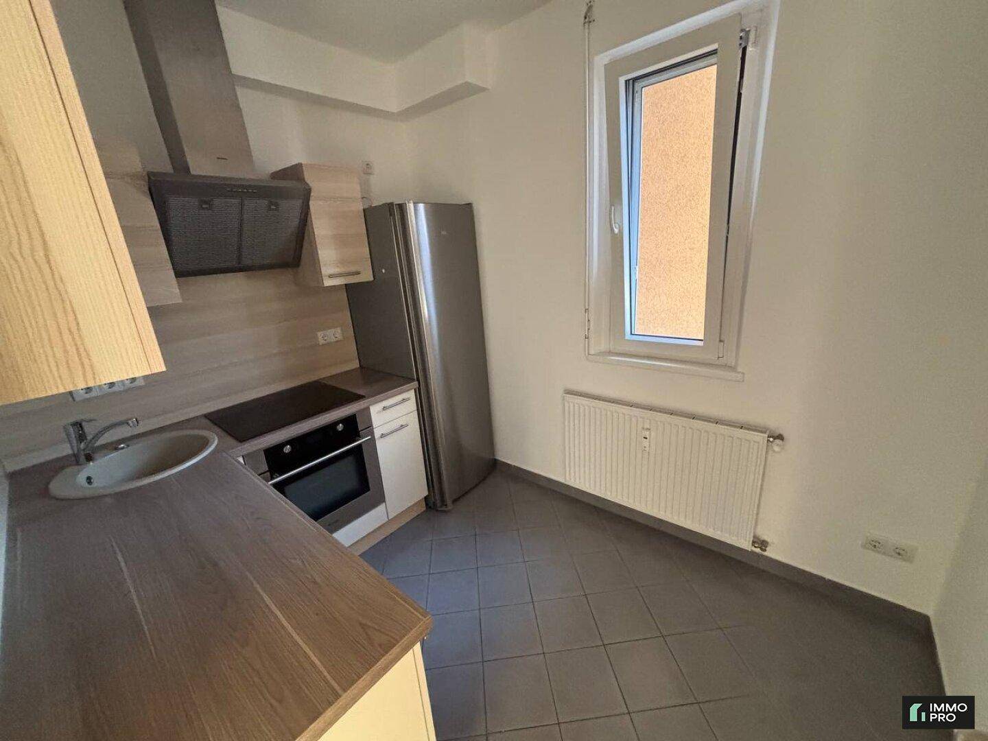 Gut ausgestattete Küche mit Holzschränken, Edelstahlgeräten und einem Fenster für Belüftung.