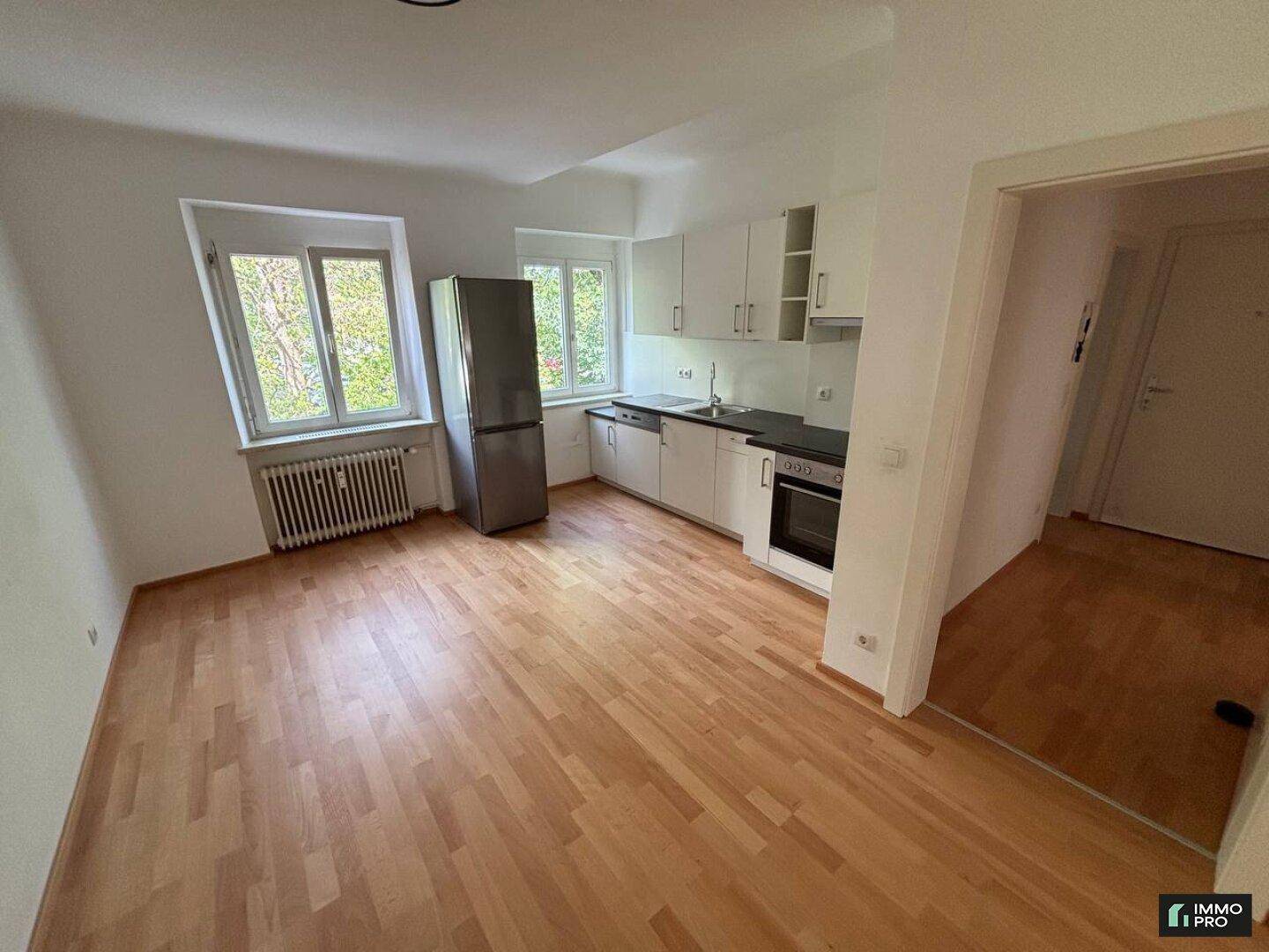 Offene Küche mit Einbauschränken, Kühlschrank und Fenster mit Blick ins Grüne.