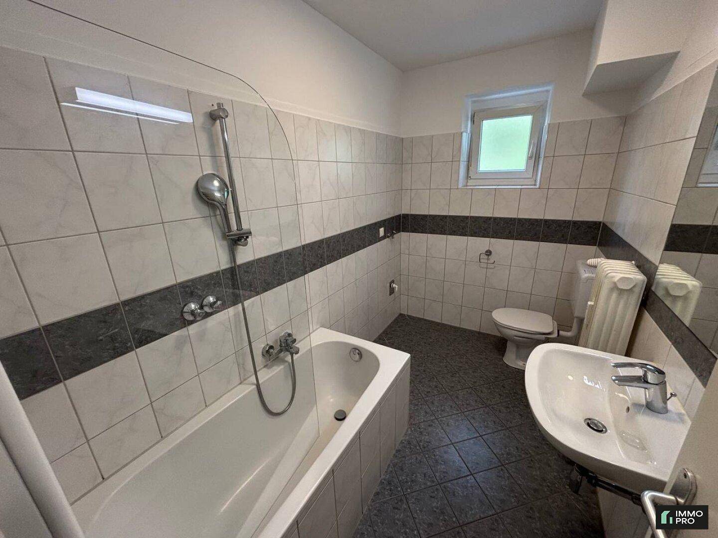 Badezimmer mit Badewanne, WC, Waschbecken und einem Fenster für Tageslicht.