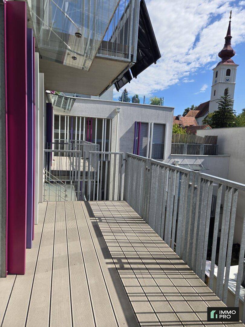 Langer Balkon mit Holzboden und Metallgeländer, bietet Blick auf die Umgebung.