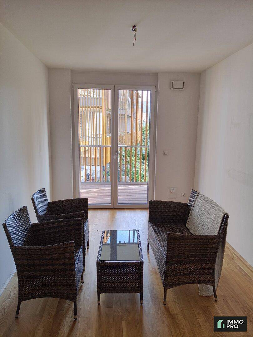 Wohnbereich mit Rattanmöbeln und Zugang zu einem Balkon, bietet eine gemütliche Atmosphäre.