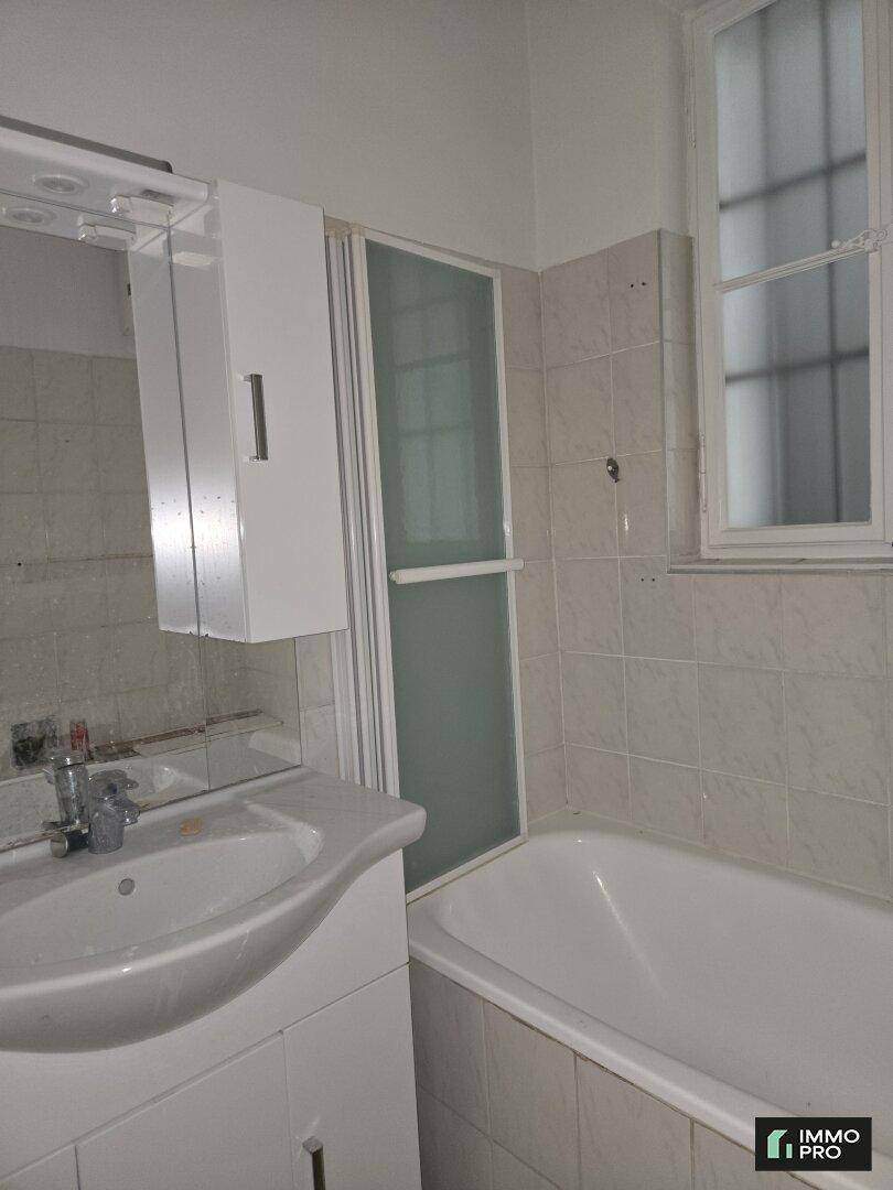 Funktionales Badezimmer mit Badewanne, Duschabtrennung, Waschbecken, Spiegelschrank und einem Fenster.