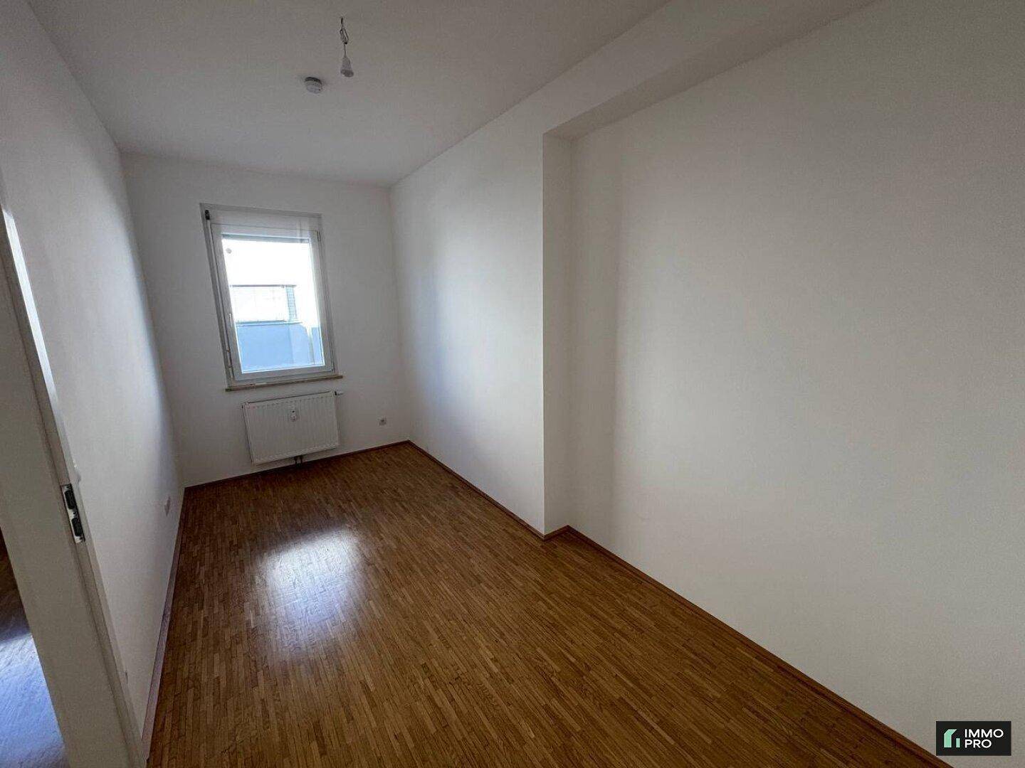 Kleinerer, heller Raum mit Parkettboden und einem Fenster, gut geeignet als Schlafzimmer oder Büro.