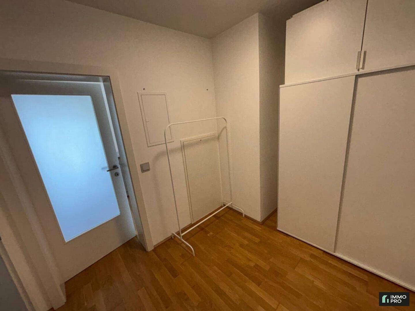 Kleines Zimmer mit Parkettboden und weißem Kleiderschrank.