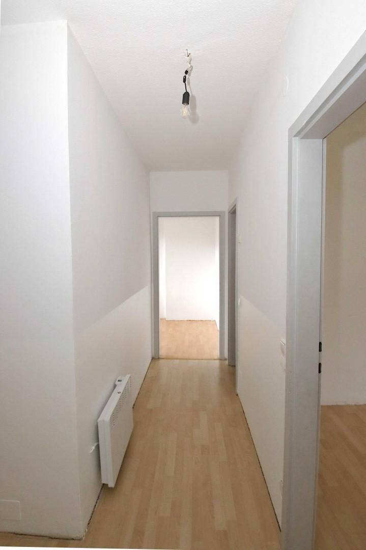 Heller Flur mit Laminatboden und weiß gestrichenen Wänden.