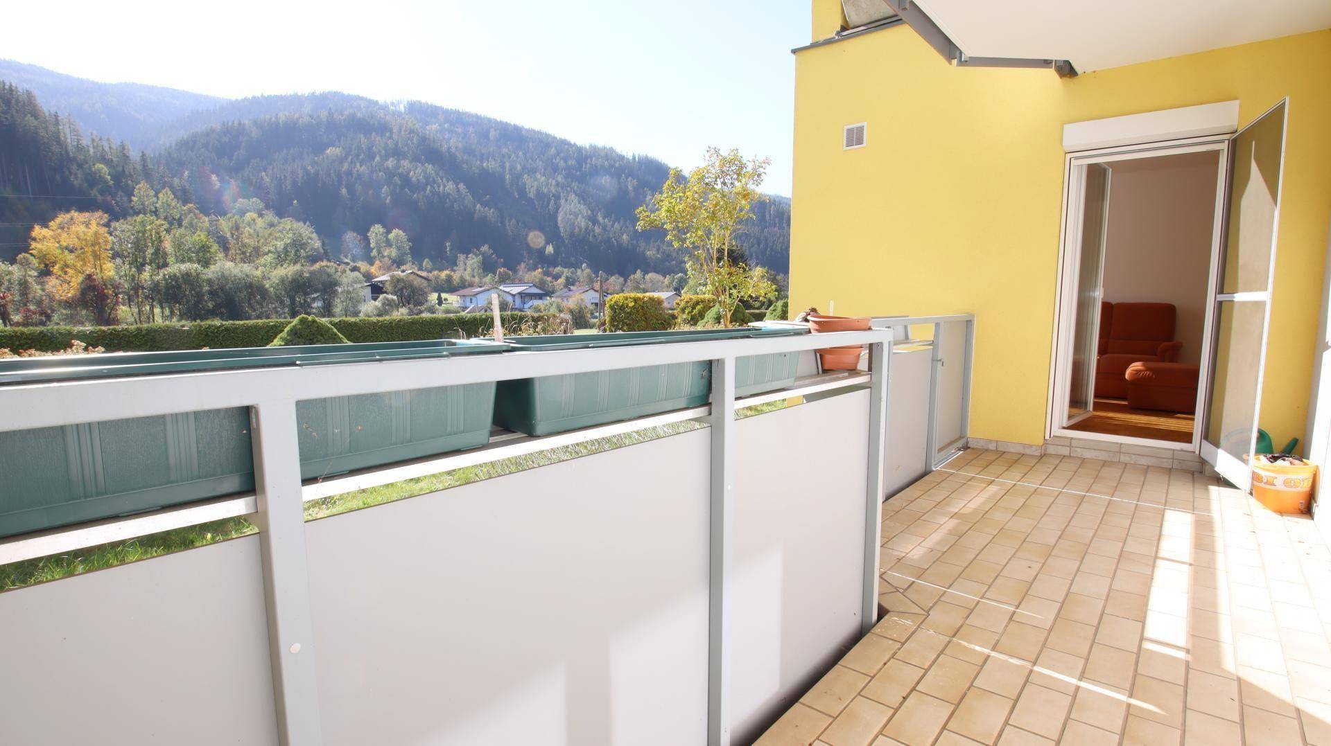 Geräumiger Balkon mit Fliesenboden und Blick auf die umliegende Berglandschaft.
