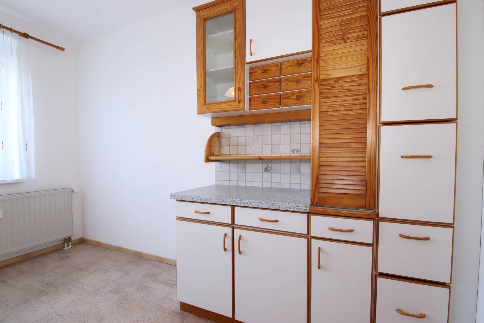 Küchenzeile mit weißen Unterschränken, Holzdetails und einem praktischen Rollladenfach.