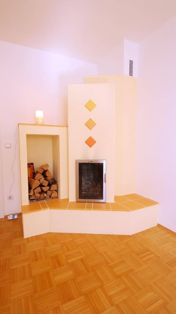 Detailansicht eines modernen Kaminofens mit Holzfach und dekorativen Fliesen im Wohnbereich.