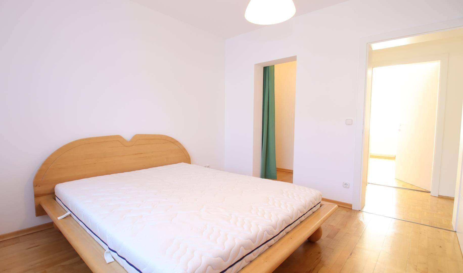 Schlafzimmer mit Holzbettrahmen und Parkettboden, bereit für individuelle Einrichtung.