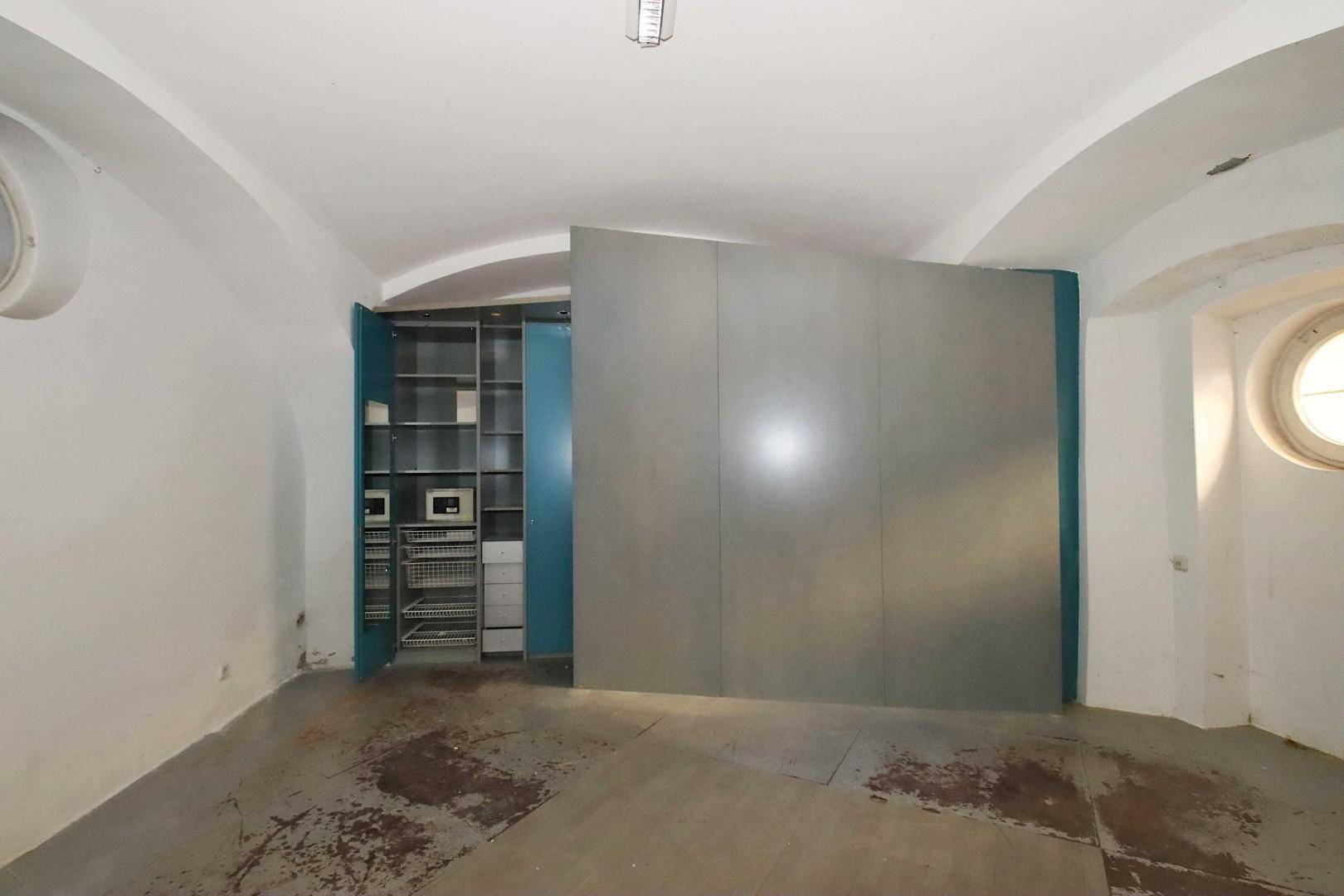 Lagerraum mit Gewölbedecken, einem großen Trennelement und einem offenen Regalsystem mit Safes.