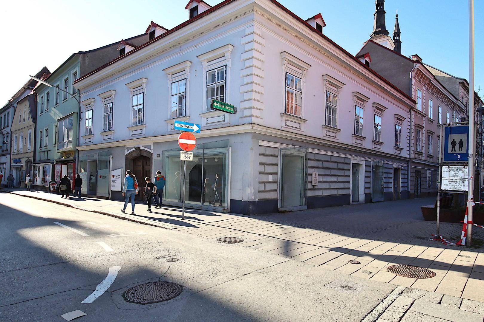 Historisches Gebäude an einer Straßenecke mit hellblauer Fassade und großen Fenstern im Erdgeschoss.