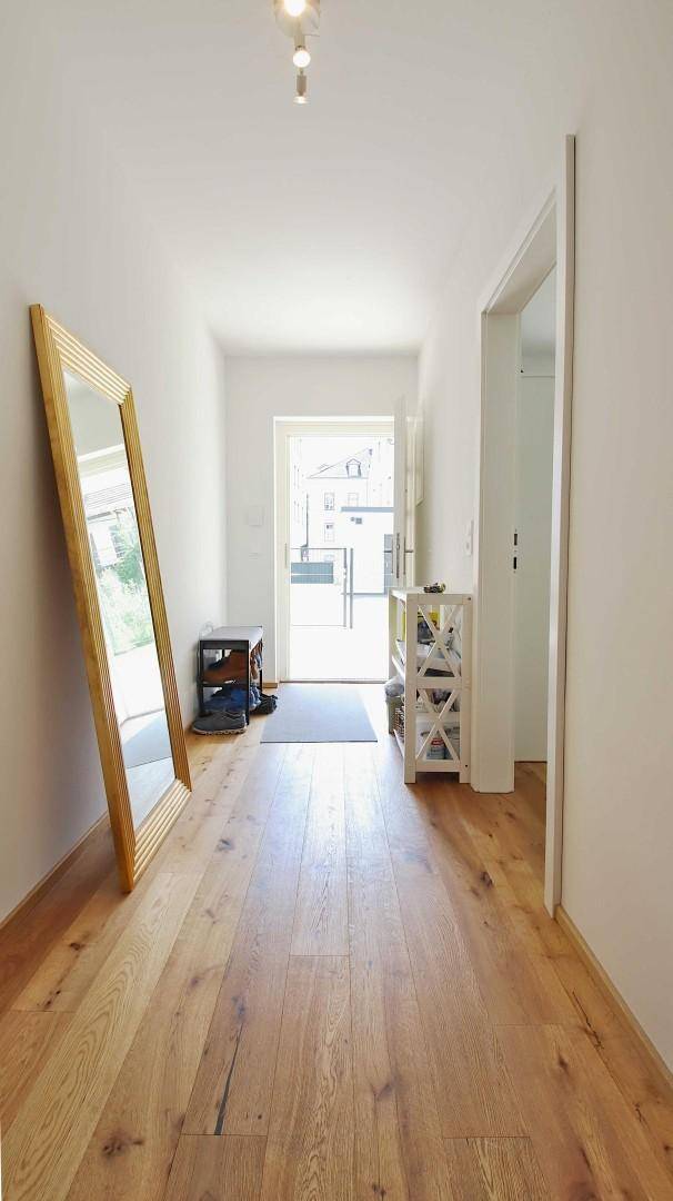 Heller Flur mit Holzboden und einem großen Spiegel, der den Raum optisch erweitert.