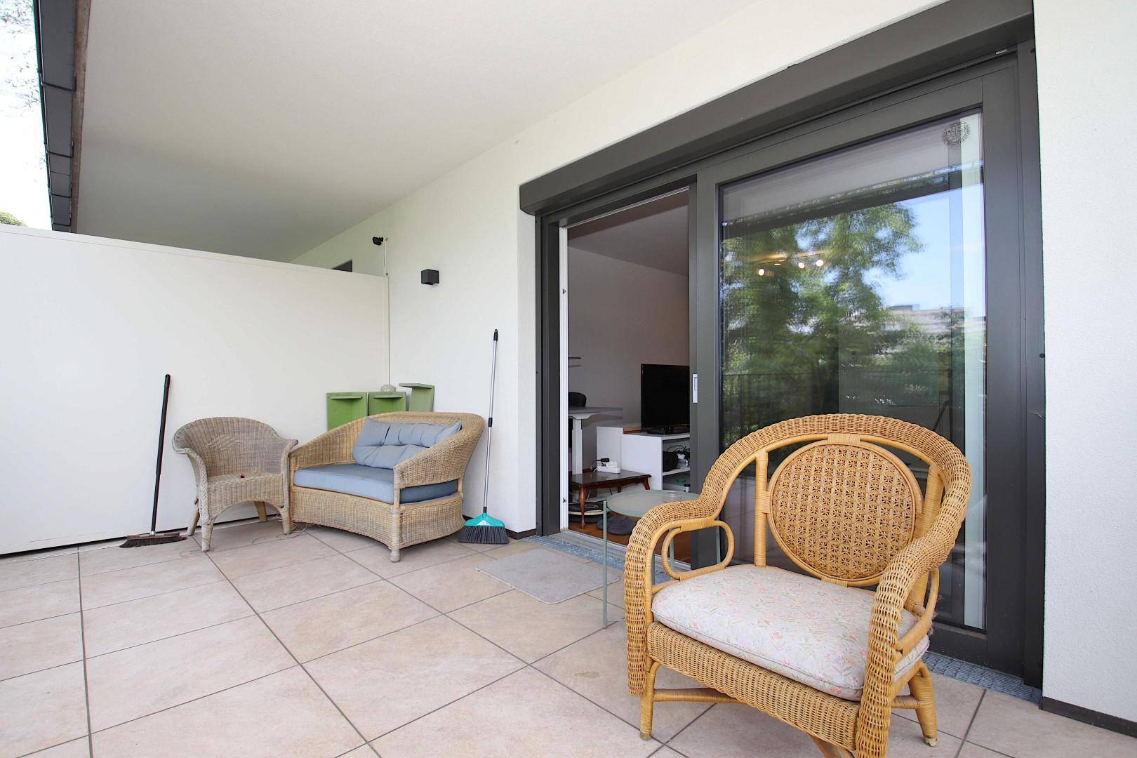 Gemütliche Terrasse mit Korbmöbeln und direktem Zugang zum Innenbereich.