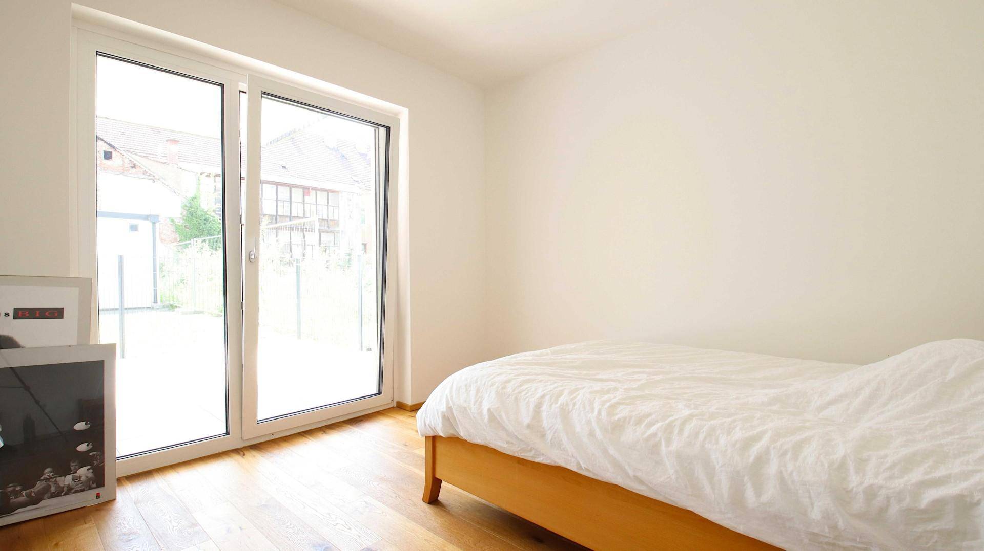 Helles Schlafzimmer mit Holzboden und einem Bett, das viel Tageslicht erhält.