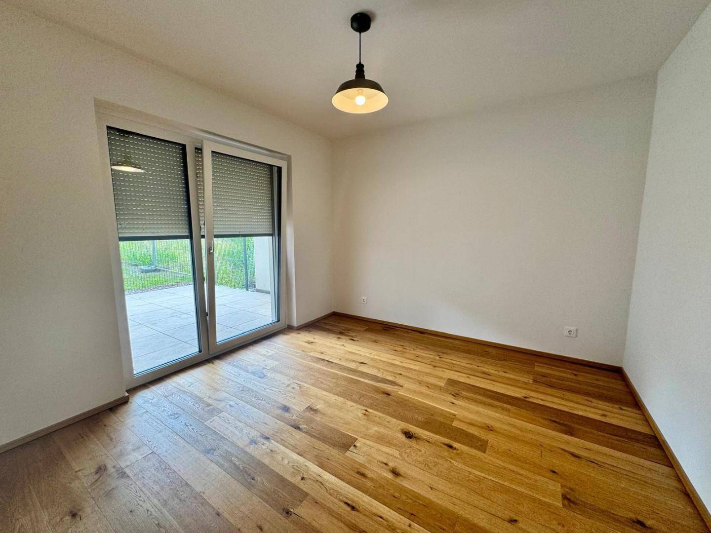 Helles Schlafzimmer mit Holzboden und Zugang zu einer Terrasse oder einem Gartenbereich.