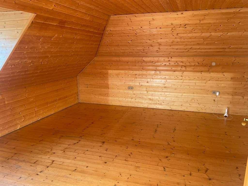 Geräumiger Raum mit durchgehender Holzverkleidung an Wänden und Decke sowie einem passenden Holzboden.