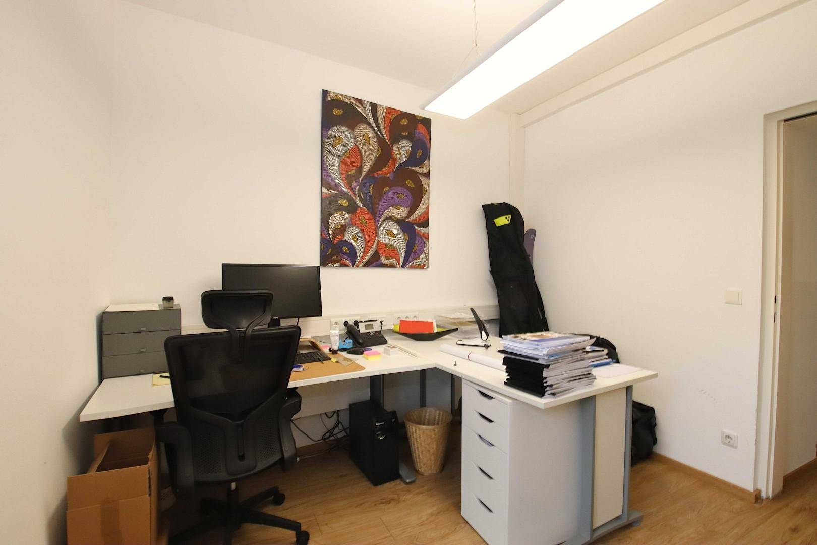Funktionales Büro mit großem Schreibtisch, Bürostuhl und Laminatboden für produktives Arbeiten.