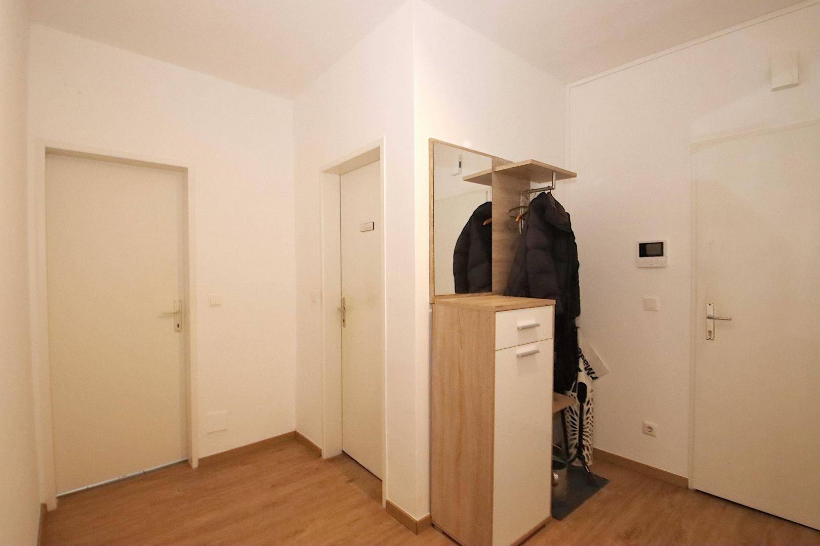 Heller Flur mit Garderobe, Spiegel und Laminatboden, ideal für den Eingangsbereich.