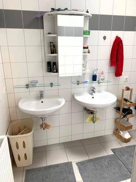 Badezimmer mit zwei Waschbecken, Spiegelschrank und weißen Fliesen, funktional und hell.