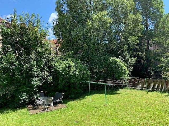 Grüner Gemeinschaftsgarten mit Sitzbereich, Wäscheleine und altem Baumbestand.
