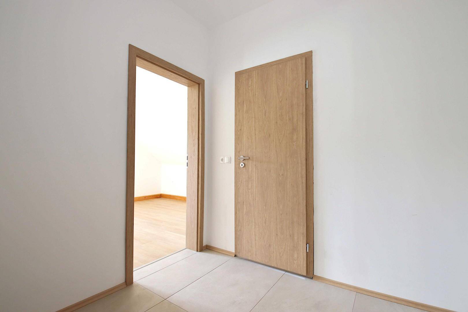 Heller Flur mit Fliesenboden und Holztüren, der zu weiteren Räumen führt.