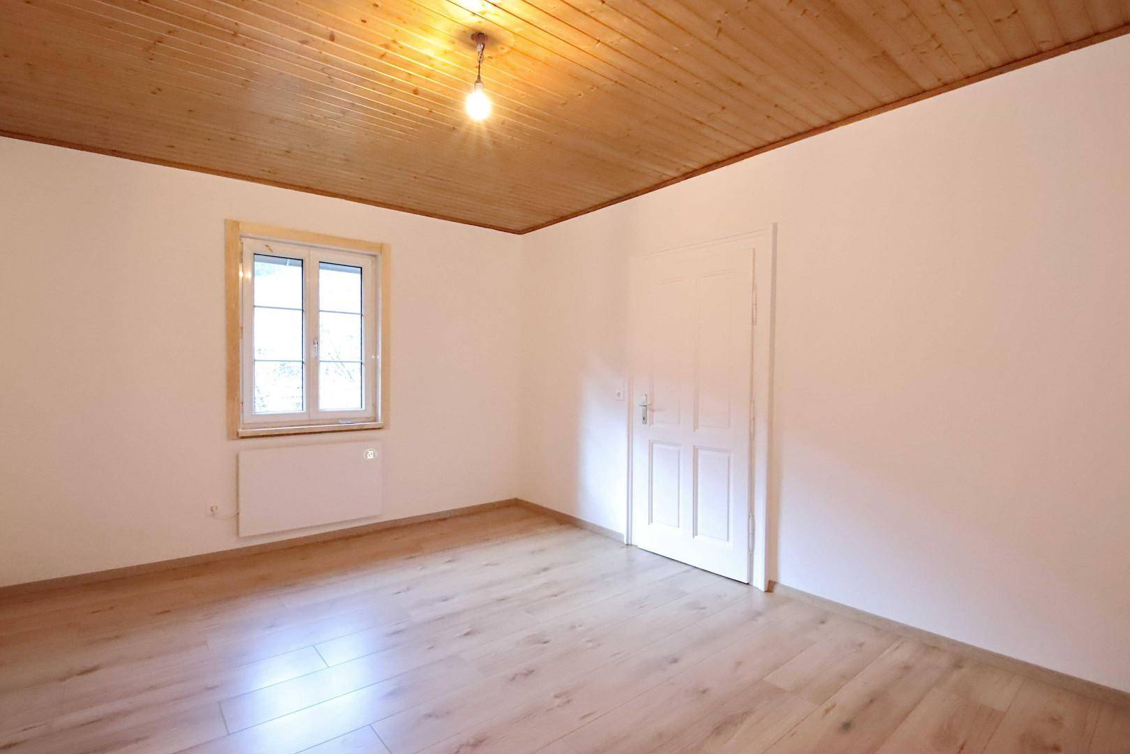 Ruhiges Zimmer mit Holzboden, Fenster und einer traditionellen Holzpaneeldecke.