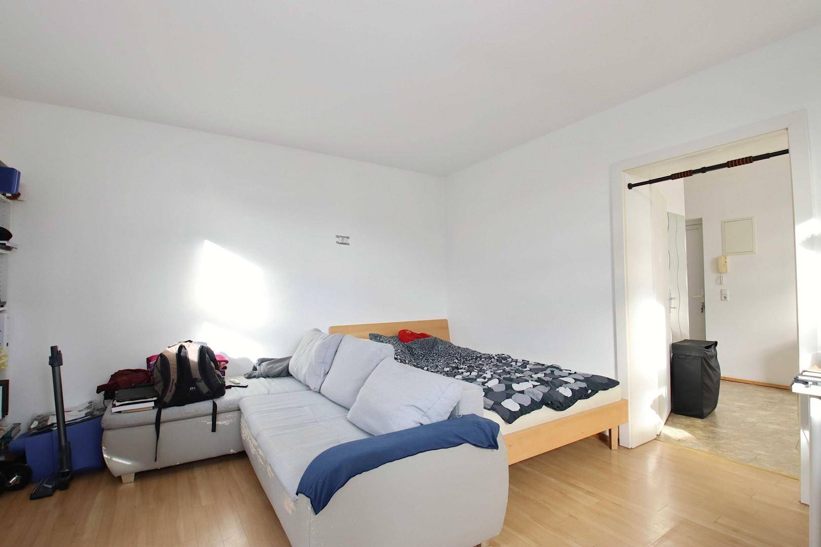 Schlafzimmer mit Bett, Sofa und hellem Holzfußboden, bietet eine entspannte Atmosphäre.