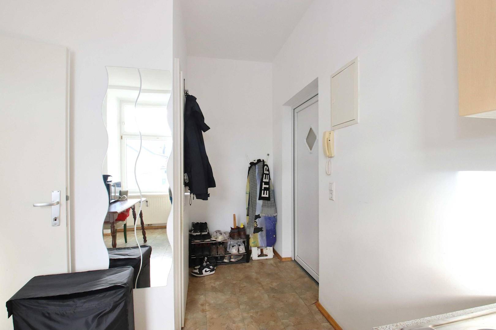 Heller Flur mit Garderobe, Spiegel und Fliesenboden, bietet praktischen Stauraum.