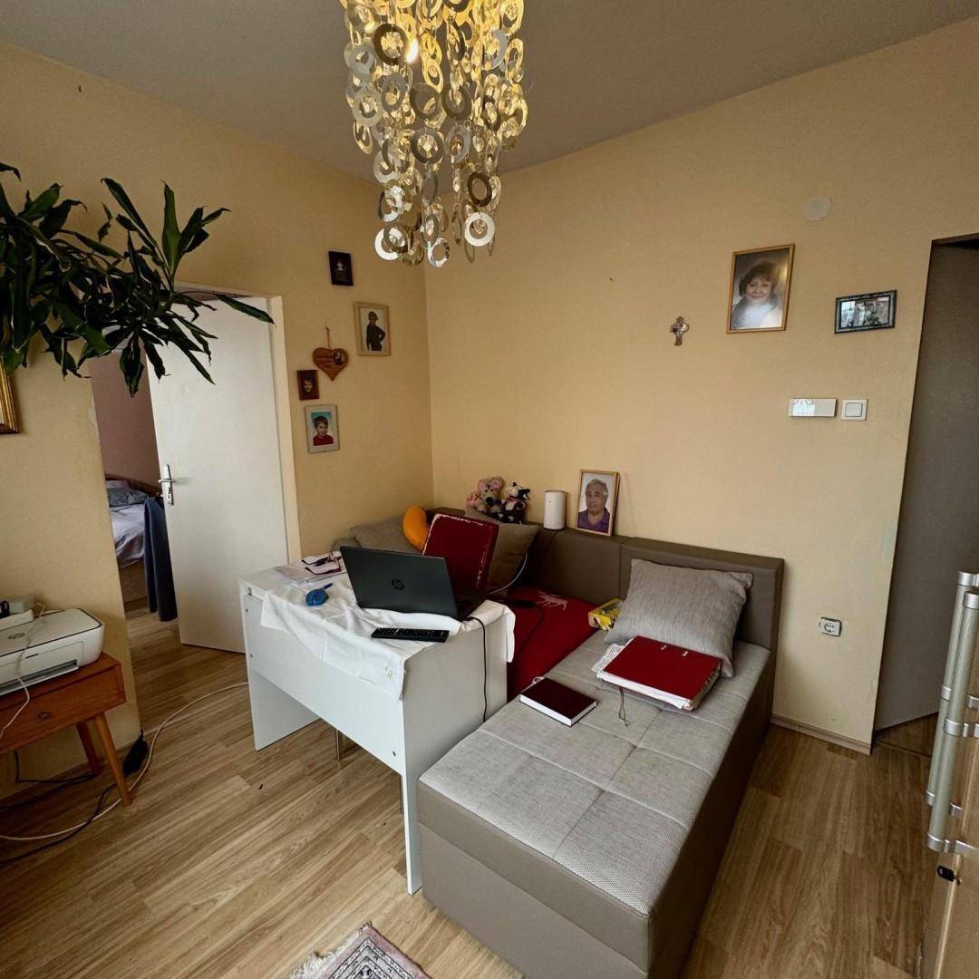 Wohnraum mit Schlafsofa, Schreibtisch und auffälligem Kronleuchter, vielseitig nutzbar und hell.