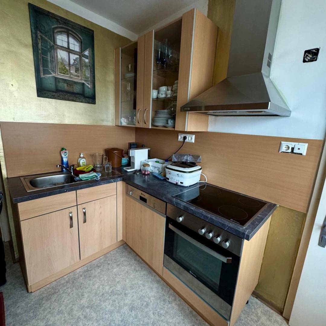 Kompakte Küchenzeile mit Holzschränken, Spüle, Induktionskochfeld und Backofen für effizientes Kochen.