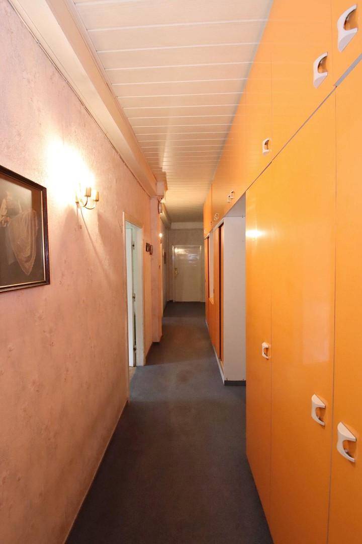 Langer Flur mit orangefarbenen Einbauschränken und Holzdecke.