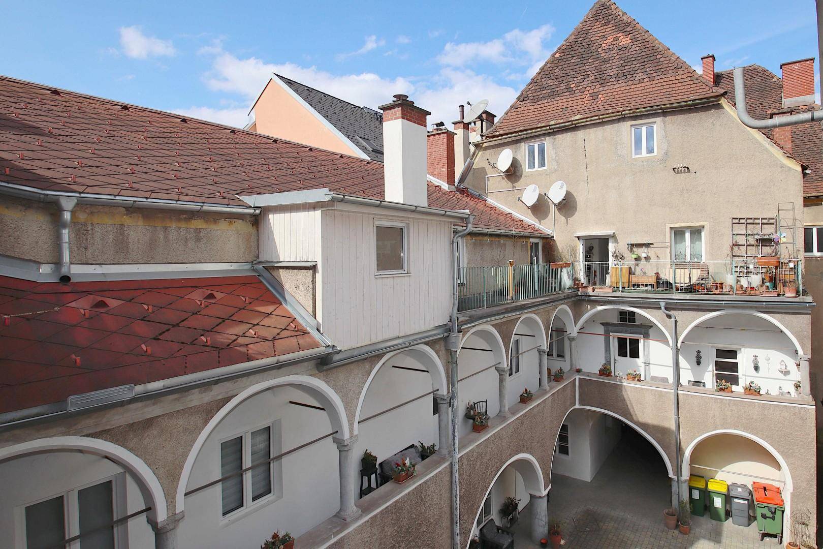 Blick auf einen traditionellen Innenhof mit Arkaden und mehreren Wohneinheiten.